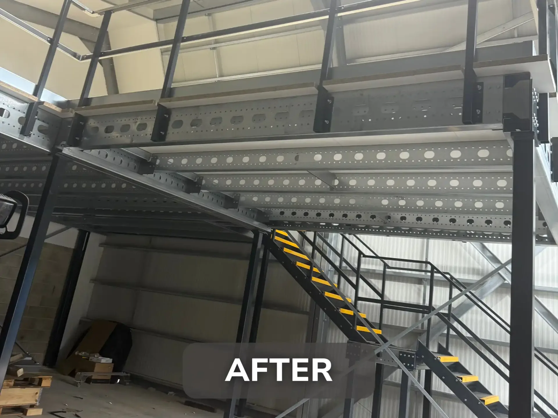 Steel mezzanine floor structure with staircase and safety handrails installed at Voltec.